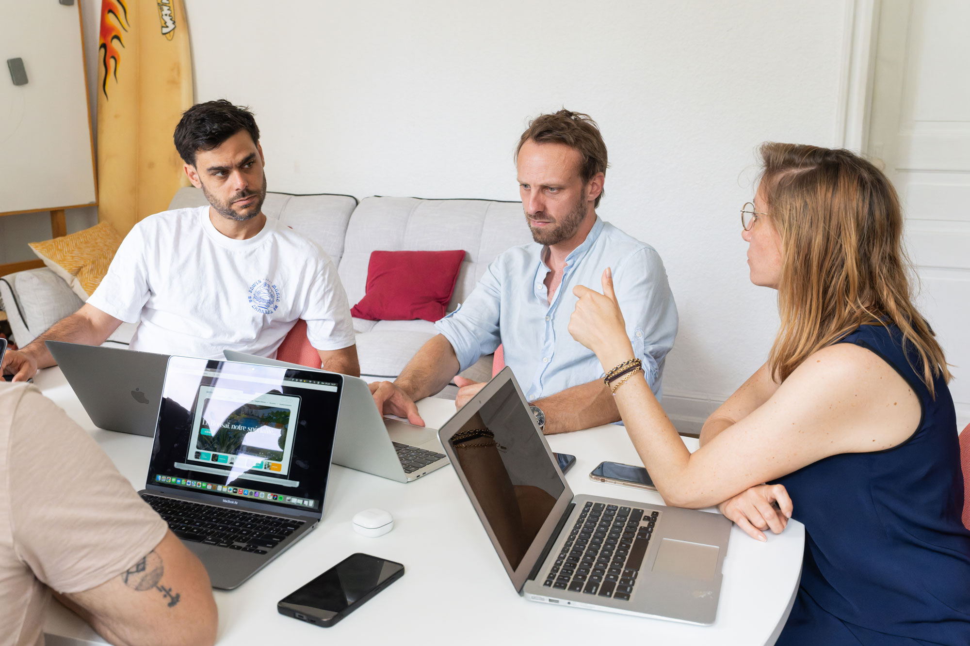 Équipe en réunion autour d’une table, travaillant sur des ordinateurs portables lors d’une session de collaboration en entreprise
