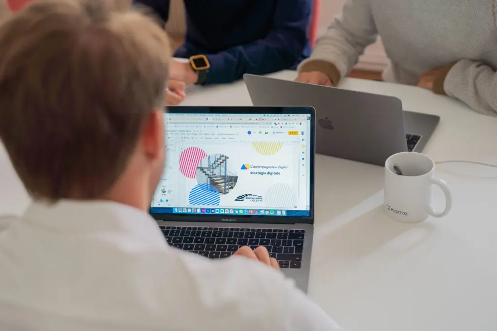 Vue arrière d'un homme concentré devant son ordinateur, travaillant sur un design UI/UX pour créer une expérience utilisateur immersive et alignée avec l'identité de marque.