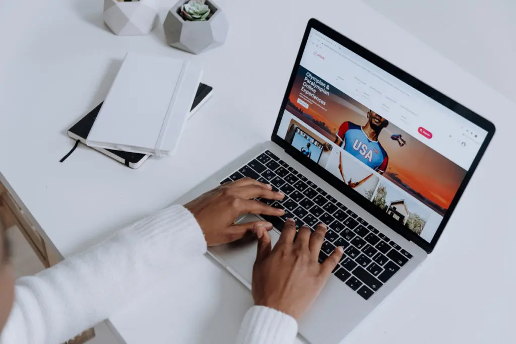 Mains d'un homme utilisant un ordinateur pour afficher un site web, symbolisant l'analyse continue et l'optimisation des plateformes digitales pour améliorer l'expérience utilisateur et le taux de conversion.