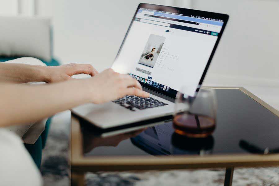 Ordinateur sur une table avec un verre, illustrant l'engagement d'une agence web envers l'éco-conception et l'hébergement durable.