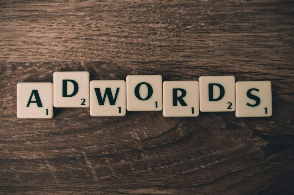 Mot « AdWords » écrit avec des lettres de jeu sur une table en bois, pour illustrer la publicité Google Ads.